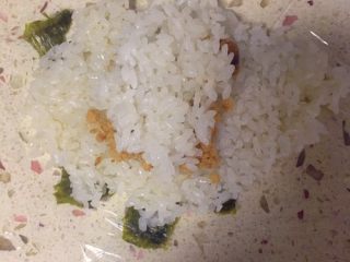 9、足球饭团,放上肉松，再取一点米饭盖在上面。同时肉松也可以换成自己喜欢吃的蔬菜呀等等，这个口味由自己来决定。