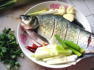 6、红烧鳊鱼,调制好的鱼放在盘里,配上姜丝,拍扁的蒜,干辣椒丝,后又加了一些大葱!几种颜色搭配看起来不错了!