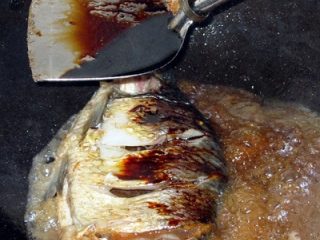11、红烧鳊鱼,然后就可以放一小碗水(家庭没有高汤)开始煮——饭店里火大油多,人家甚至全用油烹熟,家庭就用自己的做法咯!水开后加入最重要的黄酒+酱油,是个去腥调味染色的步骤!