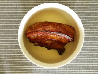 13、梅菜扣肉,炸好的五花肉取出放入事先准备好的冰水中浸泡让肉质回软。