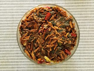 19、梅菜扣肉,将炒好的梅干菜盛入装有五花肉的碗中。