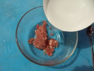 1、家庭版自制锅贴,准备100g猪肉馅倒入碗中，加入3勺清水顺时针搅拌。