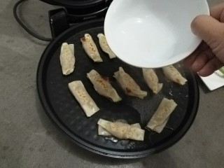 12、家庭版自制锅贴,煎制一面金黄后，翻面，加入小半碗水。
