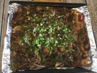 15、孜然羊腿肉,将生葱蒜撒在烤好的羊腿肉上面