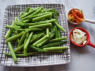 2、蚝油百合汇芦笋,将芦笋去掉较老的根部，切成3-5厘米的段，放入沸水中焯10秒钟；红辣椒切成斜刀片；大蒜切成片