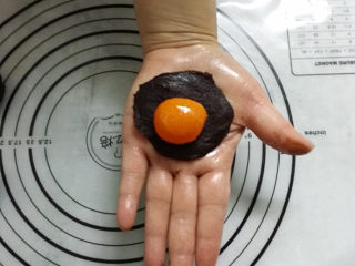 7、双色蛋黄酥,接着将配好的红豆沙分成10小份备用、取一份红豆沙压扁放入鸭蛋黄