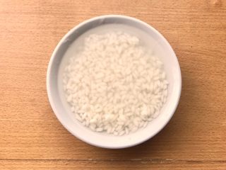 2、晚餐+一碗芝士排骨饭,先将大米放入你要吃的碗中，大概半碗的量，然后水加入到碗9分满。腌制15分钟，泡发至如图。