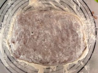8、米歇尔可可面包,手上沾干粉,将面团拍成长方形面片,厚度约4cm。