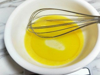 2、春节家宴饭后甜点#橙汁戚风蛋糕#,加入玉米油，用手动打蛋器打至均匀。