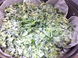 7、（两吃）莴笋叶蒸麦饭,锅中铺好龙布把拌好的莴笋叶子均匀的铺子龙布上盖上盖子，上汽后蒸8分钟关火