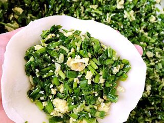 6、飘香韭菜盒,取一个面皮放入馅料包好