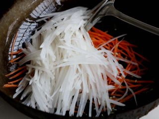 8、素炒萝卜双丝,接着倒入白萝卜丝翻炒至变色；