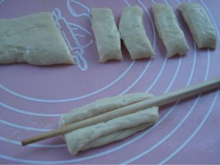 4、DIY健康酥炸小油条,第二天早上取出发好的面团，不必揉，直接在抹了油的砧板上按扁，切成小块。取两块面叠好后用筷子压一下