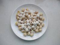 4、拔丝莲子,在捞出莲子上先撒上一大勺面粉，晃动盘子，使其均匀沾满。