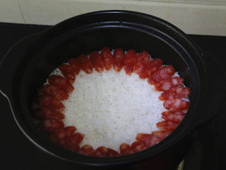 5、广式腊肠煲仔饭,煮到米饭看不见水分，出现些孔洞状态时加入腊肠，继续用小火焖两分钟