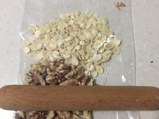 4、松软坚果布朗尼,杏仁、核桃用微波炉叮熟后放入保鲜袋里用擀面杖压碎。