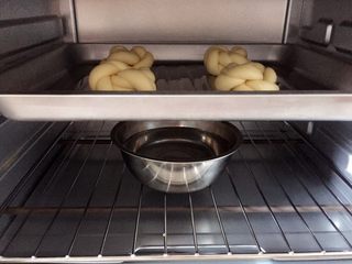 13、牛奶黑芝麻小餐包,把烤盘放入烤箱，烤箱里放盆热水，进行二次发酵。