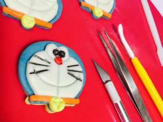 3、哆啦A梦翻糖曲奇饼干,取出熬制好的翻糖印上形状画眼睛嘴巴