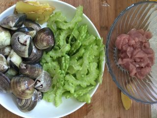 1、#文蛤苦瓜汤#,文蛤放盐水里吐净沙子后用清水洗净外壳备用。将苦瓜和瘦肉切片备用。