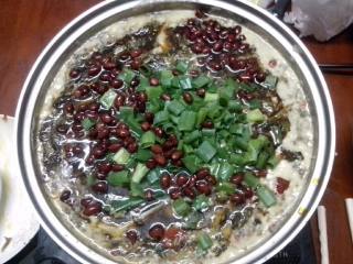 7、家庭自制酸菜鱼,将酸菜均匀的撒入锅里，煮一分钟。关火。把一大把大葱的叶子葱花 放入锅中，不要散开放中间就好。然后把辣油，炸好的花生和油一起均匀的倒入锅里。