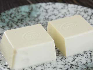 1、皮蛋豆腐—简单却不平凡的凉菜，就是它,豆腐对半切成两块（先把豆腐倒扣在盘中，剪去盒子的四个小角，再撕开包装膜比较容易整块倒出来），备用。