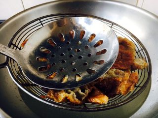 7、#绿色美食# 下饭神菜  面筋丝瓜煲,用笊篱捞出油面筋，并用勺按压油面筋，压出水分。