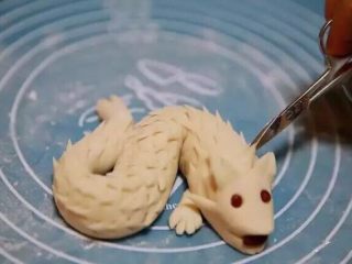 13、新年喜庆花样馒头,从头部开始用剪刀剪出小尖角，一直延续到尾巴，每一行尖角都要错开剪，在尾部中间剪开，成为尾翼。