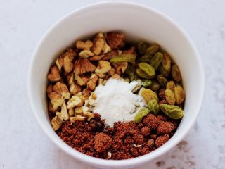 6、果仁红糖发面饼,取一个大一点的碗，放入烤好的核桃仁和葡萄干。再加入红糖，放少许面粉，放面粉是为了做饼的时候，红糖不会爆浆哟。