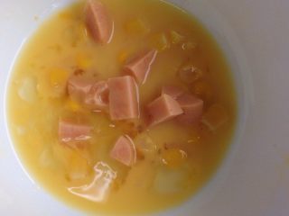 5、煎吐司块,煎完后，剩下蛋家加入罐头玉米，与火腿肠，混合均匀。