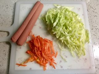 8、黄金黑米卷,胡萝卜去皮切丝，卷心菜洗净切丝，火腿肠如图对半切。