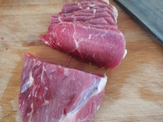 1、家庭版_葱爆小牛排,牛里脊肉提前一个小时拿出来自然解冻,不要等到完全解冻,要微冻的时候就开始切牛肉,这时候的牛肉比较好切。(如图)