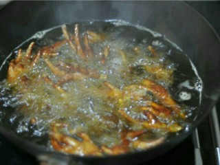 6、虎皮鸡爪,摇晃锅子，让鸡爪均匀泡在油里，待锅不再爆油时，揭开盖子，炸至皮紧发硬出纹