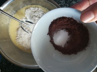 6、神奇的玛德琳,加入可可粉，泡打粉继续搅拌。别太用力，尽量不规则地搅拌，而不是顺一个方向搅拌