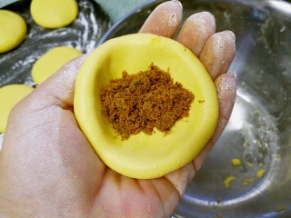6、红糖南瓜饼,揪下一小块面团，揉搓成圆球后，用拇指、食指和中指捏成中间厚四周稍薄的面窝，舀入一小勺红糖粉。