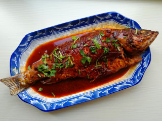 8、【豉香红烧鱼】,将鱼盛出,将汤汁浇在鱼上,撒上香菜即可