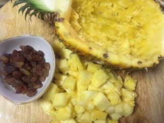4、版纳香甜糯萝饭,对剖切开分别取出果肉切小丁，葡萄干也切一下