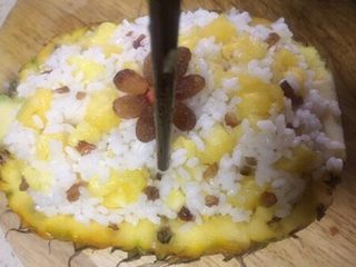 10、版纳香甜糯萝饭,再取几颗葡萄干做装饰，用筷子给菠萝饭插数个小孔以便上汽
