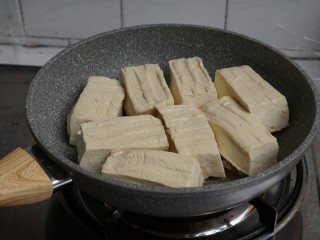 13、煎酿豆腐,转中火，将豆腐有馅的一面朝下，一块块放在锅里。